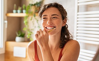 Woman smiling while brushing her teeth