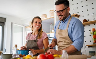 Couple smiling while preparing dinner in kitchen