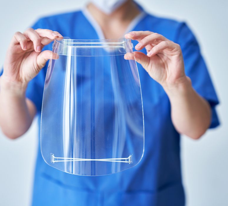 Dental team member holding up a face shield