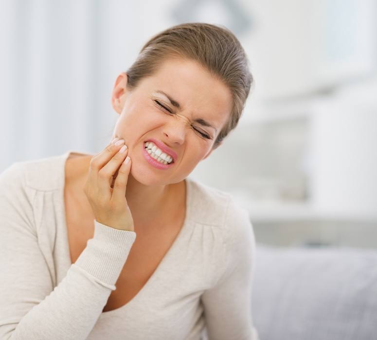 Woman in need of emergency dentistry holding jaw