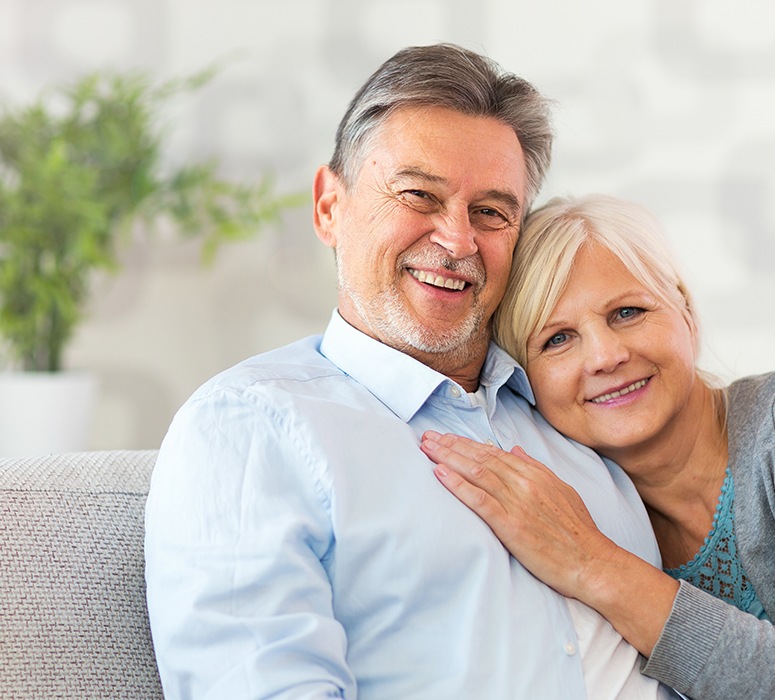 Man and woman smiling after dental crown restorations