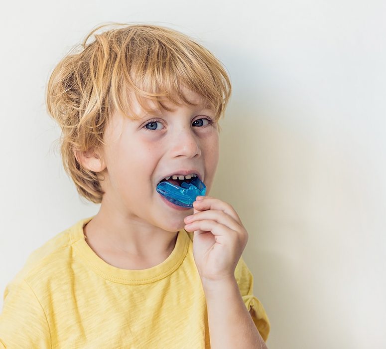 Child placing athletic mouthguard