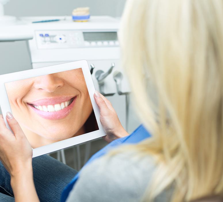 Woman looking at virtual smile design on tablet computer