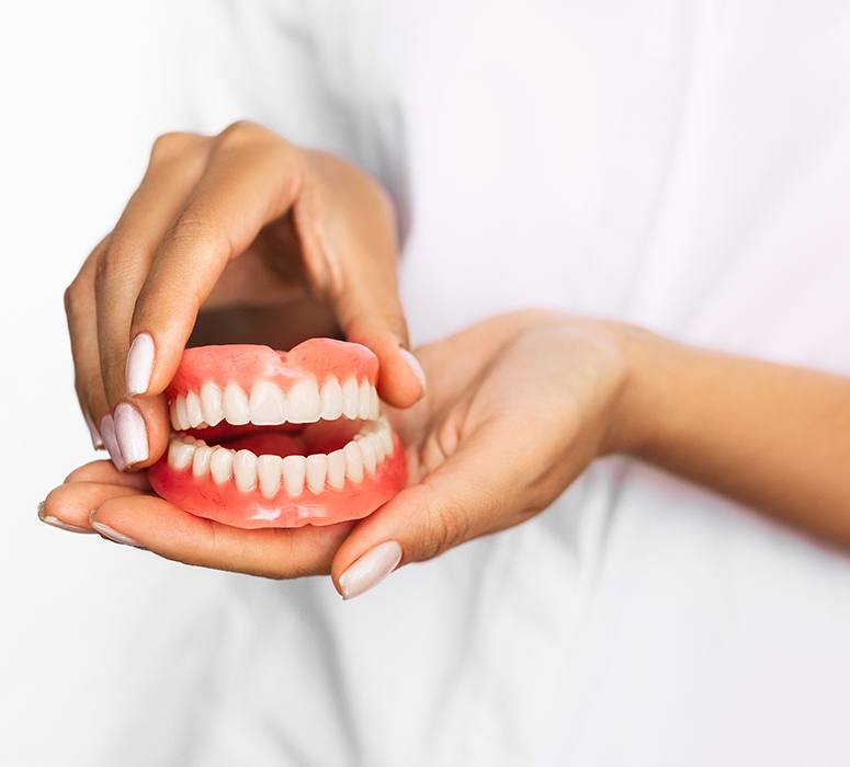 Hands holding full set of dentures