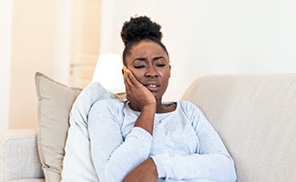 Woman with toothache sitting on couch at home