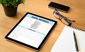 Dental insurance form on tablet next to notepad
