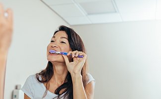 Woman brushing her teeth in bathroom