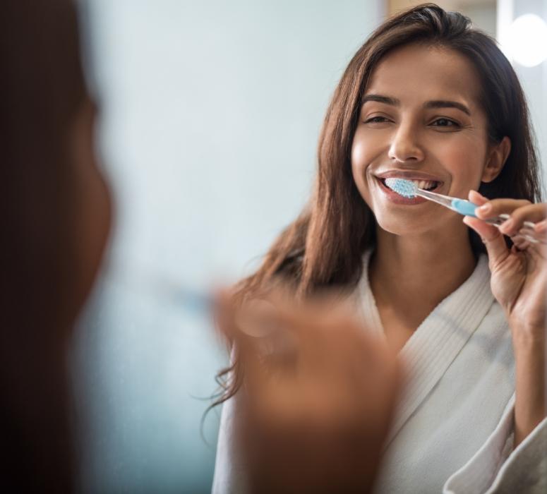 Woman brushing teeth to prevent dental emergency