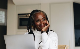 Woman smiling while working on laptop at home