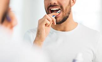 a man in a white shirt brushing his teeth