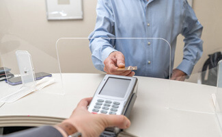 an adult man paying the cost of dental implants