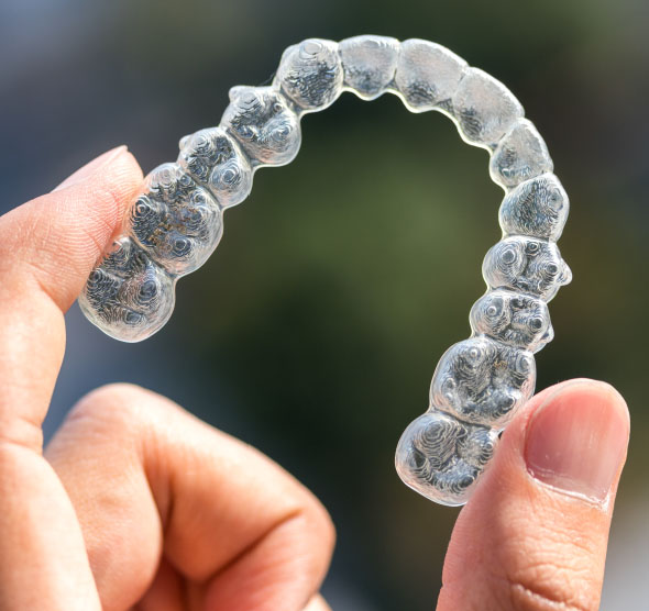 Hand holding a clear aligner