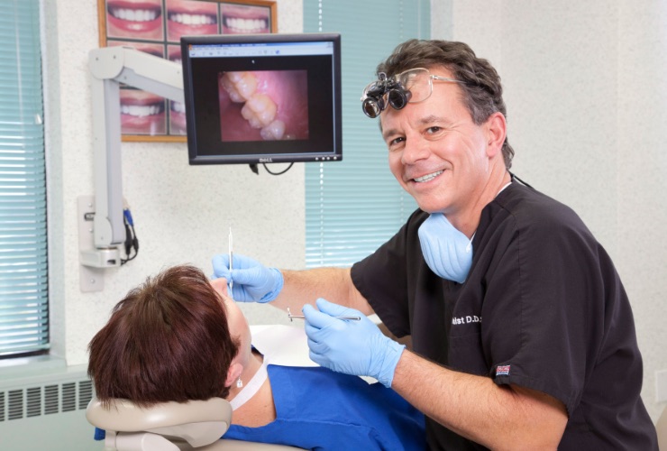 Smiling dentist treating dental patient