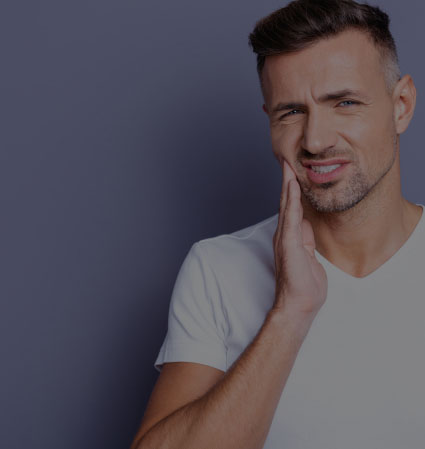 Man in white T shirt holding his jaw in pain