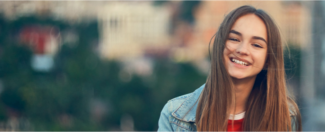 Young girl in denim shirt smiling outdoors