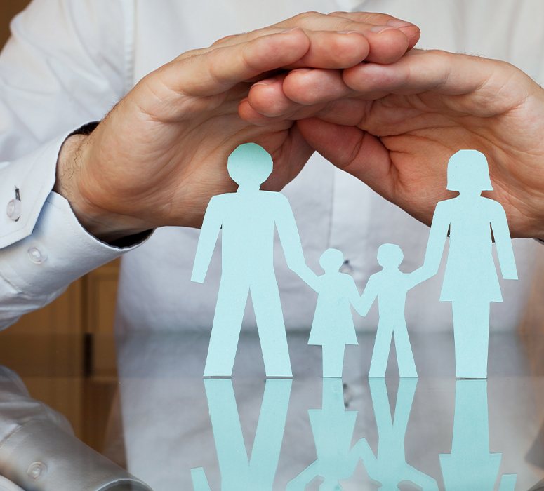 Hands covering paper cut outs of a family