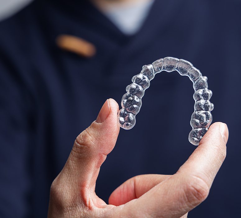 a dentist holding an Invisalign aligner