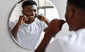 Man smiling while flossing teeth at restaurant