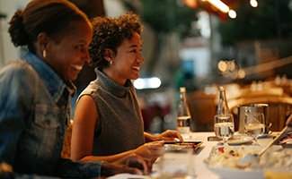 Two woman smiling at dinner in restaurant
