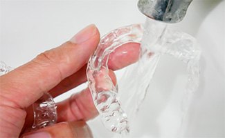 Invisalign patient in Beachwood cleaning their aligners