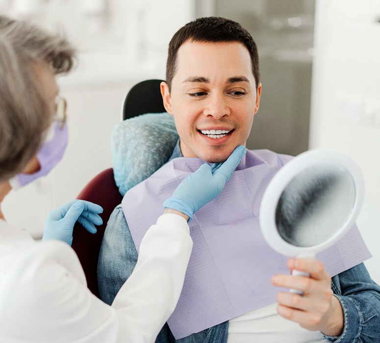 Man smiling at reflection in mirror with dentist