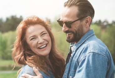 Man and woman smiling after replacing missing teeth