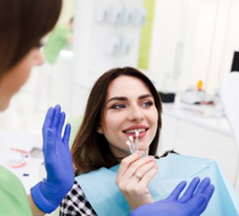 Smiling patient selecting shade of veneers at consultation