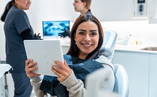 Woman smiling while holding mirror in treatment chair