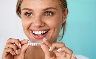 Smiling patient holding teeth whitening tray