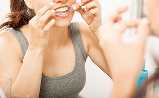 Woman putting on teeth whitening strip at home