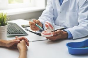 Dentist holding a dental diagram while sitting at a desk across from a patient