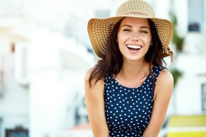 Woman smiling and wearing a sun hat during summer. 