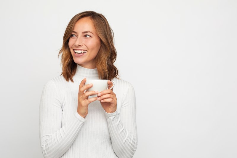 a woman smiling while drinking coffee