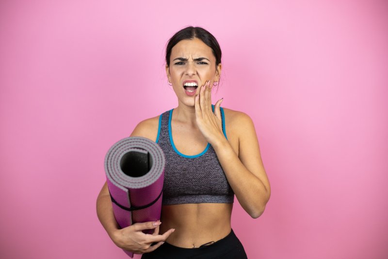 woman in exercise gear holding cheek