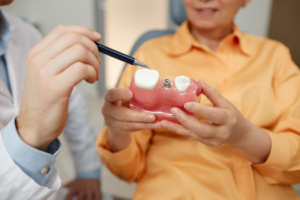 a patient and dentist examining a dental implant model